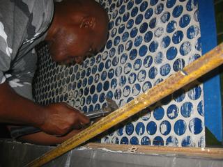 El Sr. José Bastián Cortijo, restaurador, en el proceso de remoción de la pega adherida a los azulejos del vestíbulo azul. / Foto por: Santiago Gala Aguilera